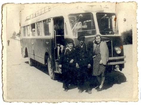 Zdjęcie archiwalne. Na nim powojenny autobus, przed którym stoją trzy osoby.