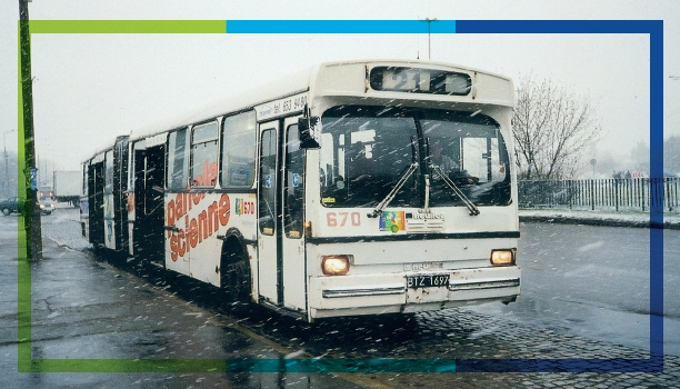 Zdjęcie archiwalne. Autobus przegubowy marki Heuliez zadysponowany w linii 21 stojący na przystanku. Na zewnątrz intensywny opad śniegu z deszczem.