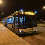 Przegubowy autobus marki Solaris zadysponowany w linii 5 stojący na przystanku. Zdjęcie wykonane nocą.